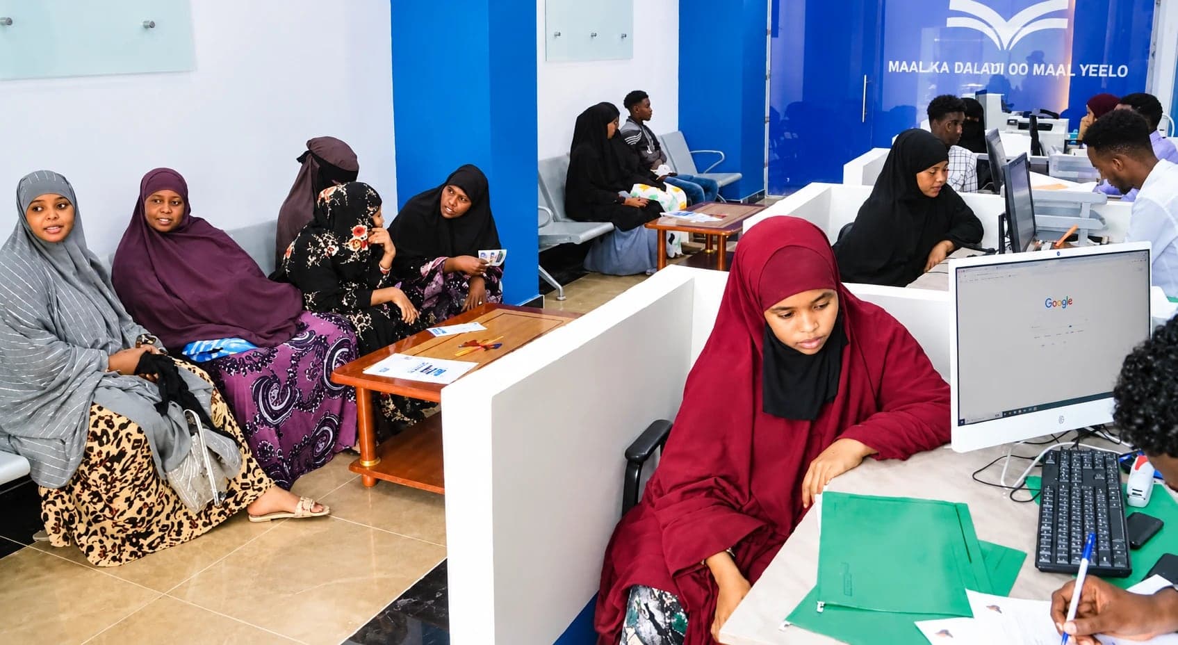 Customers wait in the Maal Microfinance branch while staff at service desks help clients